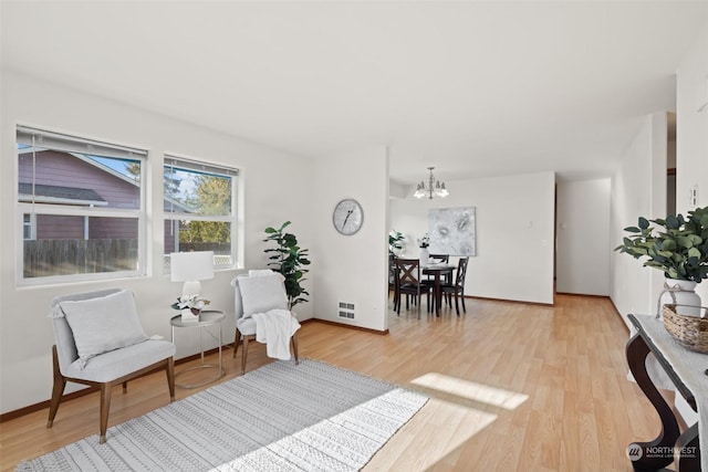 living area featuring light wood-type flooring and an inviting chandelier