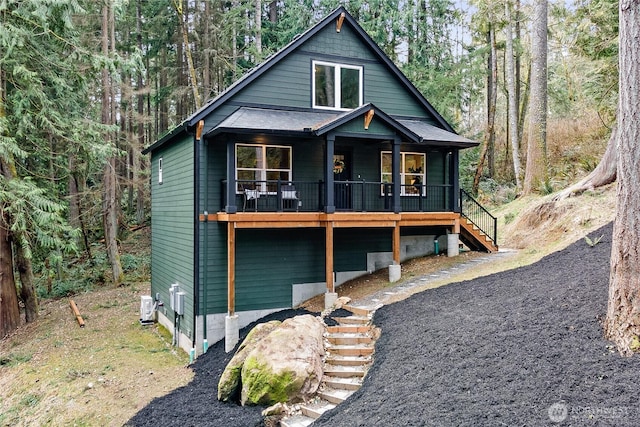 chalet / cabin featuring cooling unit, a view of trees, and stairs