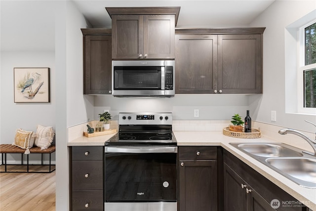 kitchen with a sink, appliances with stainless steel finishes, light countertops, and dark brown cabinets