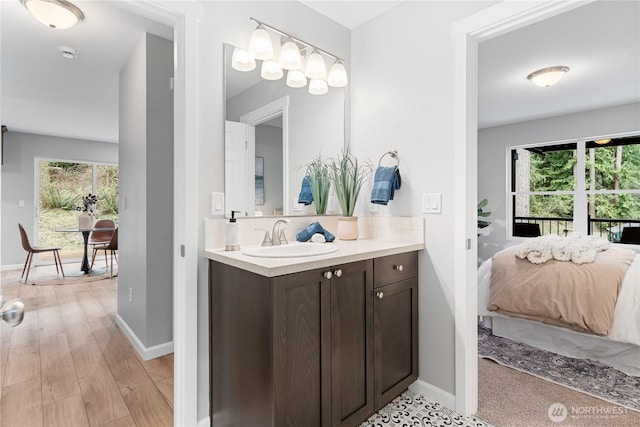 ensuite bathroom with plenty of natural light, ensuite bath, wood finished floors, and vanity