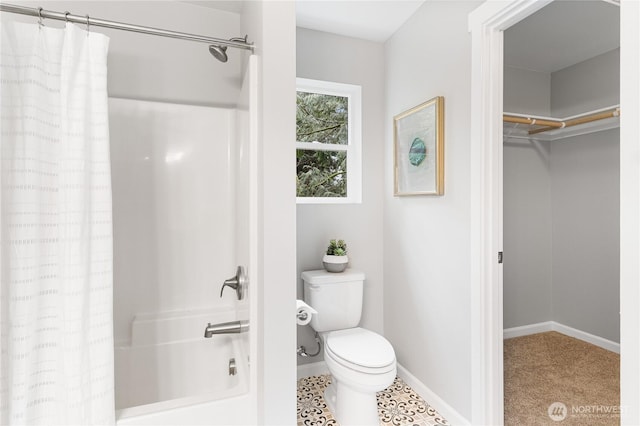 full bath featuring a walk in closet, shower / tub combo, toilet, and baseboards