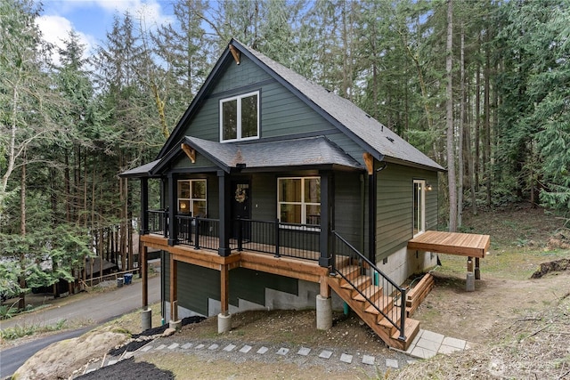 chalet / cabin with aphalt driveway, a garage, covered porch, and roof with shingles