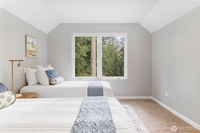 bedroom featuring light colored carpet, baseboards, and vaulted ceiling