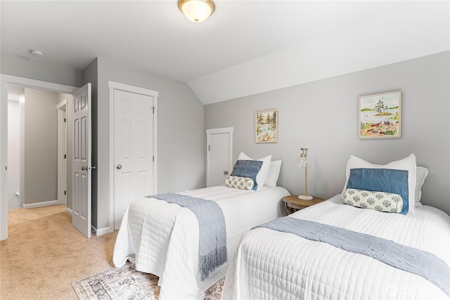 bedroom with baseboards, light carpet, a closet, and vaulted ceiling