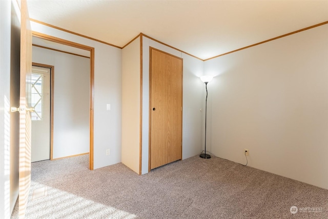 unfurnished bedroom with crown molding, carpet floors, and a closet