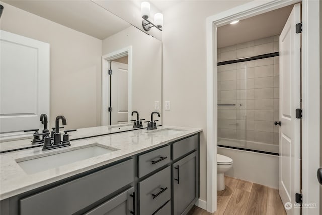 bathroom featuring a sink, toilet, wood finished floors, and double vanity