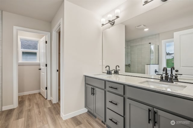 bathroom with tiled shower, vanity, and hardwood / wood-style floors