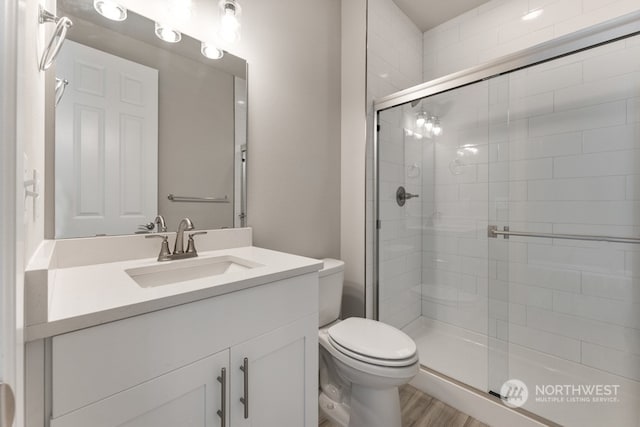 bathroom featuring vanity, toilet, a shower with shower door, and hardwood / wood-style flooring