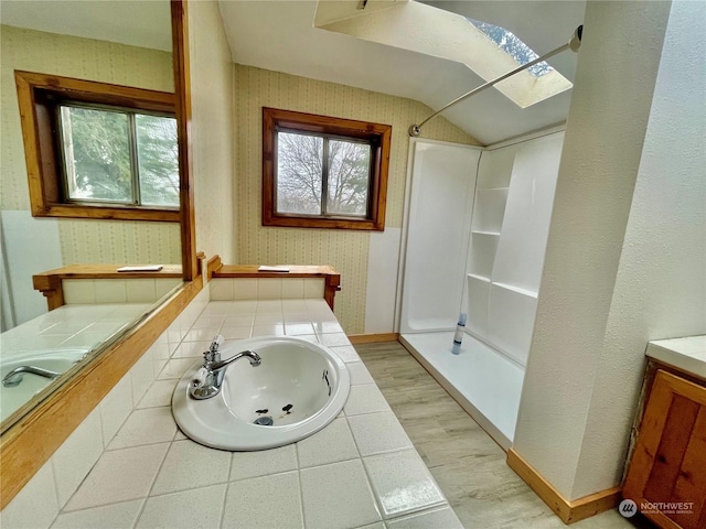 bathroom with walk in shower, vanity, and vaulted ceiling with skylight