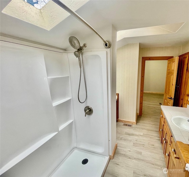 bathroom with hardwood / wood-style flooring, vanity, and walk in shower