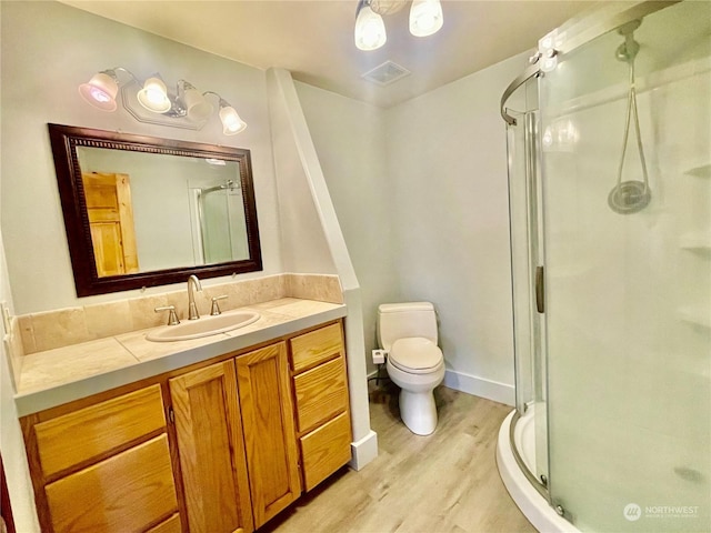 bathroom featuring an enclosed shower, vanity, wood-type flooring, and toilet