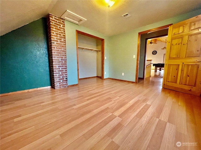 unfurnished bedroom with vaulted ceiling, a closet, and light hardwood / wood-style flooring