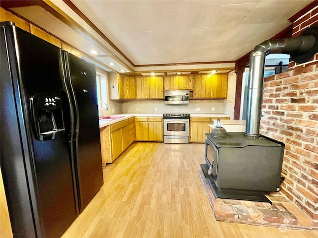 kitchen featuring sink, tasteful backsplash, light wood-type flooring, a wood stove, and appliances with stainless steel finishes