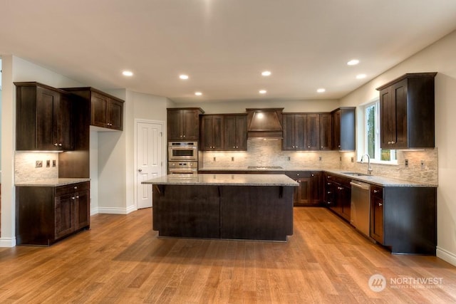 kitchen with sink, a center island, custom range hood, and light wood-type flooring