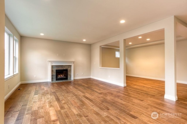 unfurnished living room with light wood-type flooring and a tiled fireplace