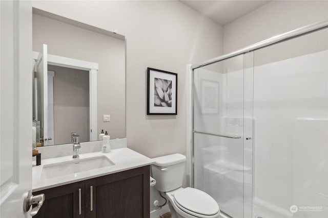 bathroom with a shower with shower door, toilet, and vanity