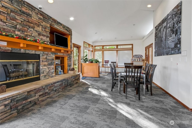 dining room with dark carpet and a stone fireplace