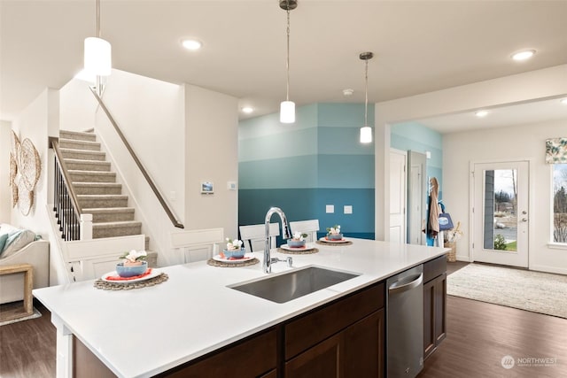 kitchen with dishwasher, an island with sink, sink, hanging light fixtures, and dark brown cabinets