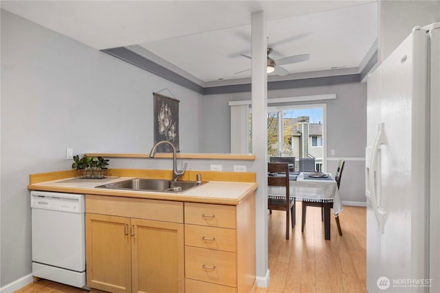 kitchen with white appliances, light wood-style flooring, light countertops, and a sink