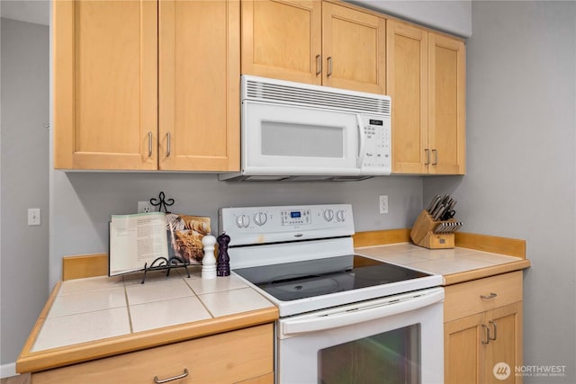 kitchen featuring white appliances, tile countertops, and light brown cabinetry