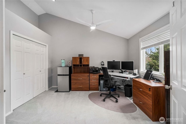 office space with vaulted ceiling, a ceiling fan, and light carpet