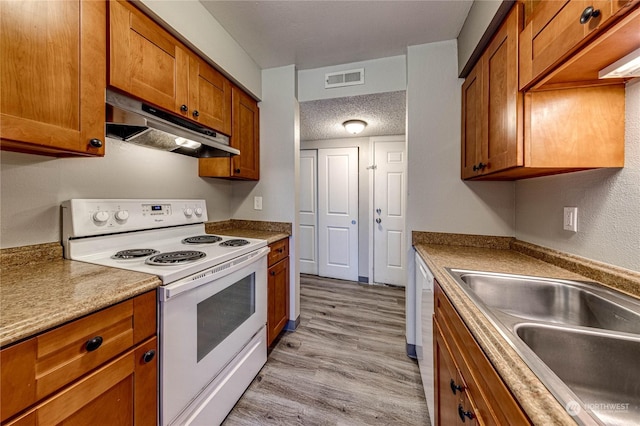 kitchen featuring sink, white appliances, a textured ceiling, and light wood-type flooring