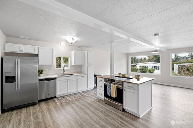 kitchen featuring light hardwood / wood-style flooring, sink, white cabinetry, beam ceiling, and stainless steel appliances