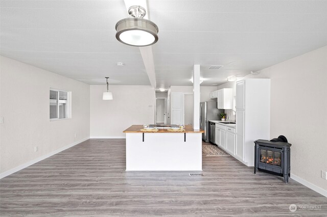 kitchen featuring butcher block counters, white cabinets, light wood-type flooring, sink, and pendant lighting