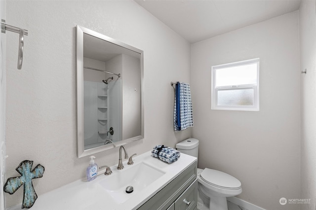 bathroom with toilet, a shower, and vanity