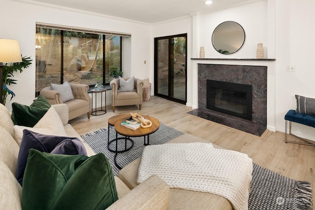 living room with light wood-type flooring, a premium fireplace, and ornamental molding