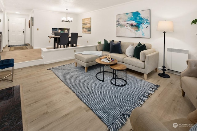 living room featuring light hardwood / wood-style floors, a chandelier, radiator, and ornamental molding