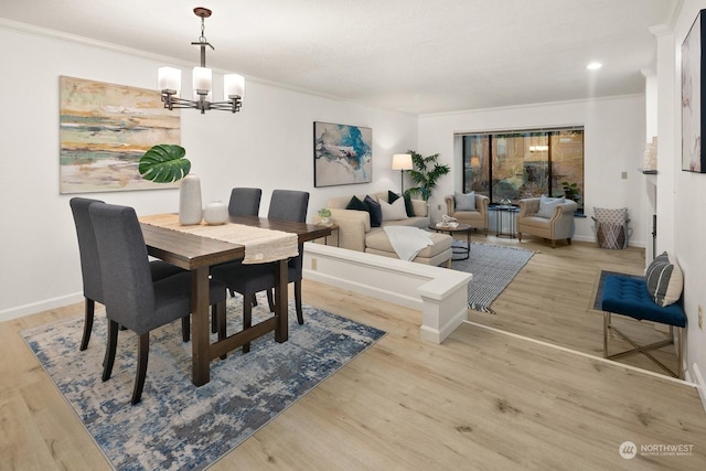 dining area featuring light hardwood / wood-style flooring, crown molding, and a chandelier