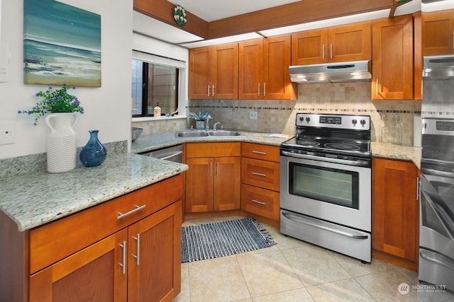 kitchen with backsplash, light tile patterned floors, light stone countertops, and appliances with stainless steel finishes