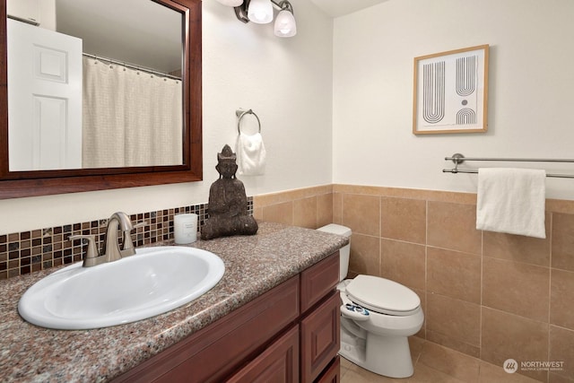 bathroom featuring vanity, toilet, and tile walls