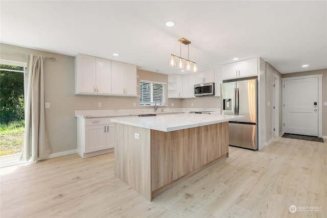 kitchen featuring a kitchen island, pendant lighting, white cabinets, stainless steel appliances, and light wood-type flooring