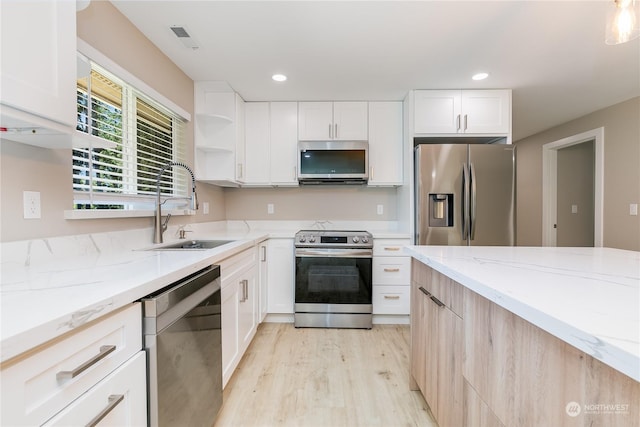 kitchen featuring sink, light stone counters, white cabinetry, light hardwood / wood-style flooring, and stainless steel appliances