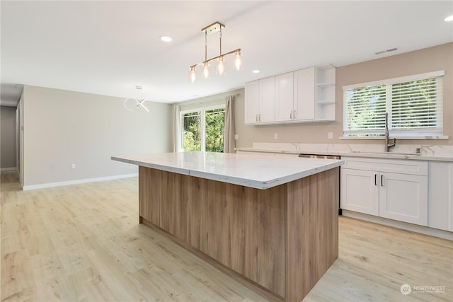 kitchen featuring white cabinetry, a kitchen island, sink, and pendant lighting