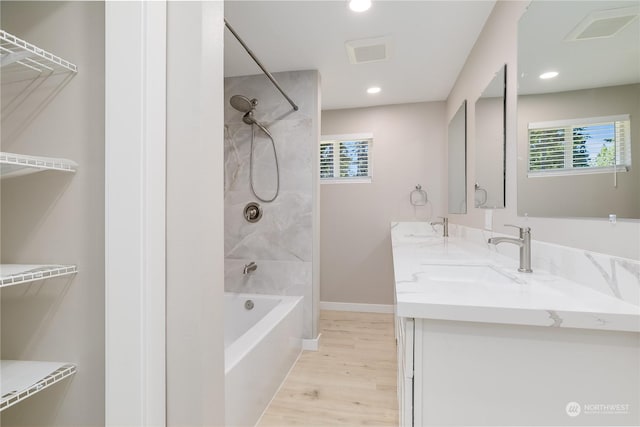 bathroom featuring hardwood / wood-style flooring, tiled shower / bath, plenty of natural light, and vanity