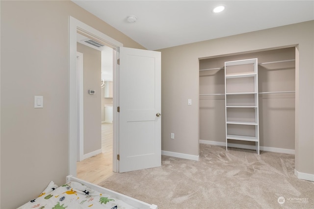 unfurnished bedroom featuring light carpet and a closet