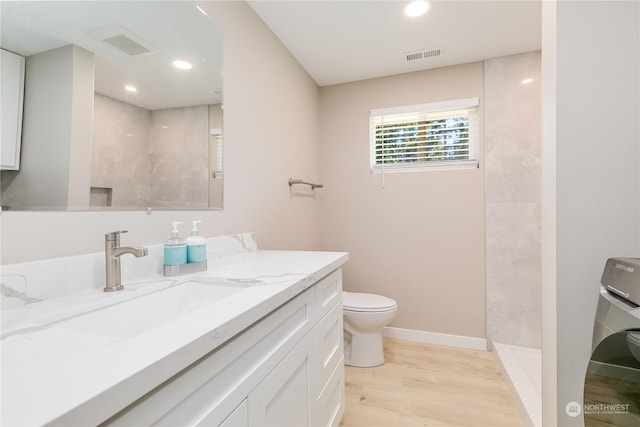 bathroom featuring walk in shower, toilet, vanity, washer / clothes dryer, and hardwood / wood-style floors