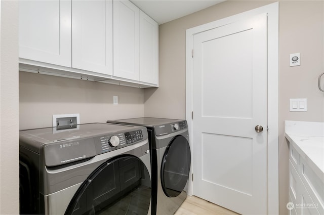 laundry area with washing machine and dryer, cabinets, and light wood-type flooring