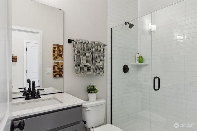 bathroom featuring toilet, a shower with shower door, and vanity