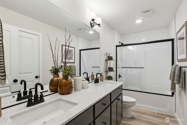 full bathroom with vanity, toilet, bath / shower combo with glass door, and wood-type flooring