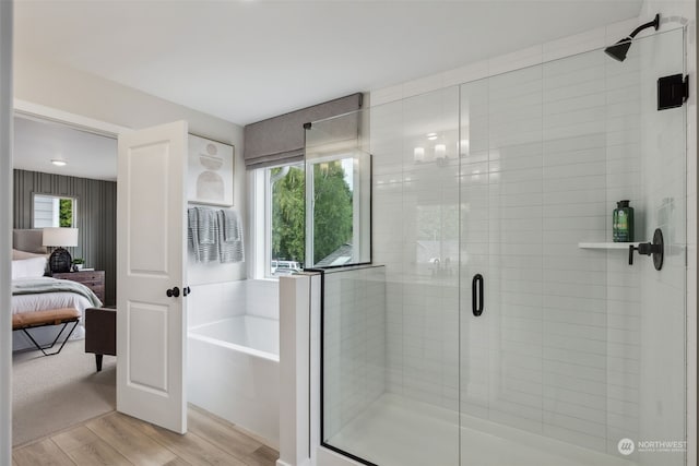 bathroom with plus walk in shower, a healthy amount of sunlight, and wood-type flooring