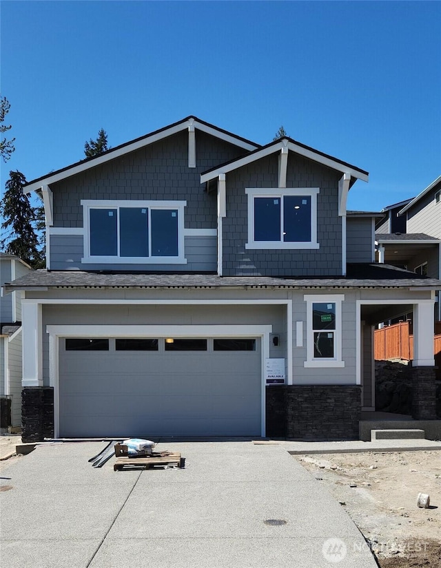 craftsman-style home with concrete driveway, central AC, stone siding, and a garage
