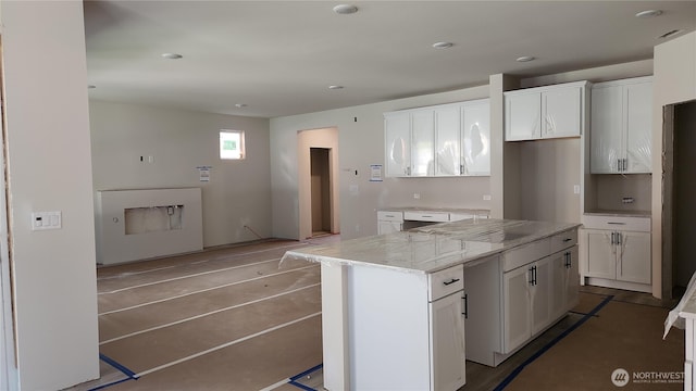 kitchen with a kitchen island, white cabinetry, light stone counters, and recessed lighting