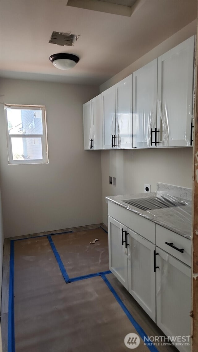 washroom featuring baseboards, hookup for a washing machine, a sink, cabinet space, and hookup for an electric dryer