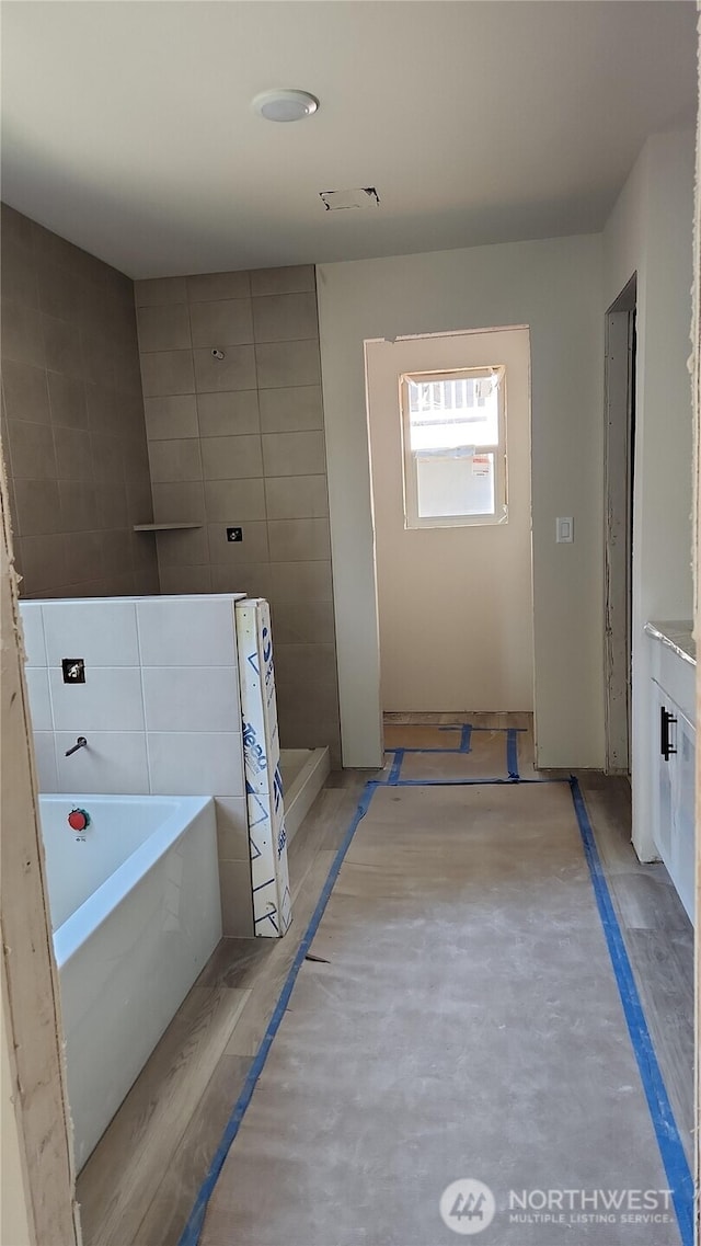bathroom with a washtub and tiled shower