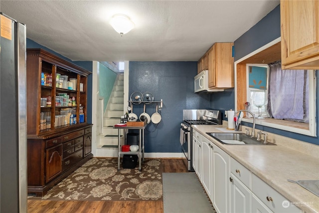 kitchen with sink, white cabinetry, stainless steel gas range oven, a textured ceiling, and dark hardwood / wood-style flooring