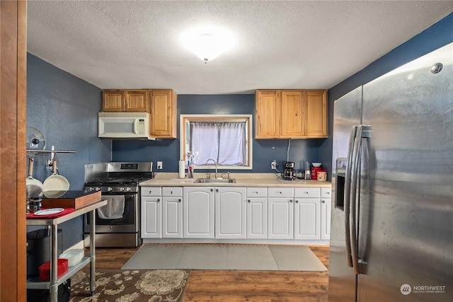 kitchen with stainless steel appliances, sink, hardwood / wood-style floors, and a textured ceiling